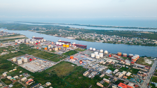 Aerial view of Satellite Town featuring industrial oil storage tanks cargo ships docked along the waterway and surrounding residential areas in Lagos Lagos Nigeria.