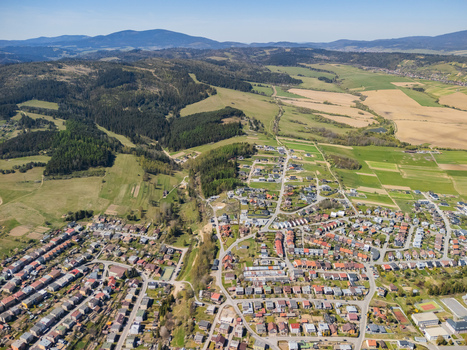 Aerial view of residential houses and lush green fields with rolling forested hills under a clear blue sky Namestovo Zilina Region Slovakia. Aerial view of residential houses and lush green fields with rolling forested hills under a clear blue sky Namestovo Zilina Region Slovakia.