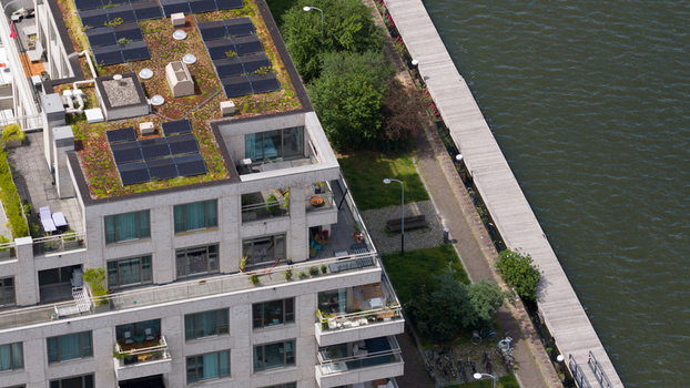 Aerial view of a modern residential building with a green roof and solar panels situated along the waterfront at Cruquiusweg in Amsterdam Noord Holland Netherlands.