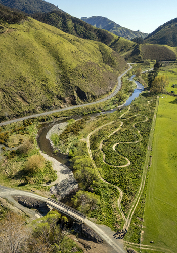 Aerial view of restored wetlands featuring winding trails a meandering stream and a small bridge set against rolling green hills in Cable Bay Nelson Region New Zealand. Aerial view of restored wetlands featuring winding trails a meandering stream and a small bridge set against rolling green hills in Cable Bay Nelson Region New Zealand.
