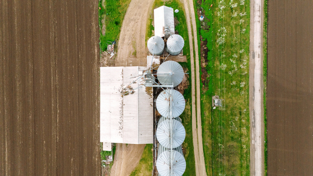 Aerial view of farm buildings and silos nestle between fields of earthy brown and patches of vivid green Sremska Mitrovica Vojvodina Serbia. Aerial view of farm buildings and silos nestle between fields of earthy brown and patches of vivid green Sremska Mitrovica Vojvodina Serbia.
