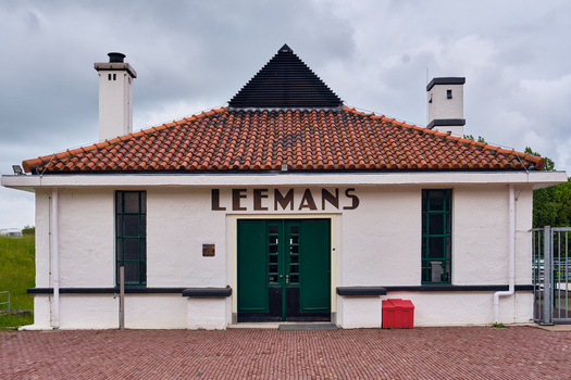 Wieringerwerf Netherlands 17 May 2026 View of the historic Gemaal Leemans pumping station featuring a red tiled roof white facade and green doors under a cloudy sky.