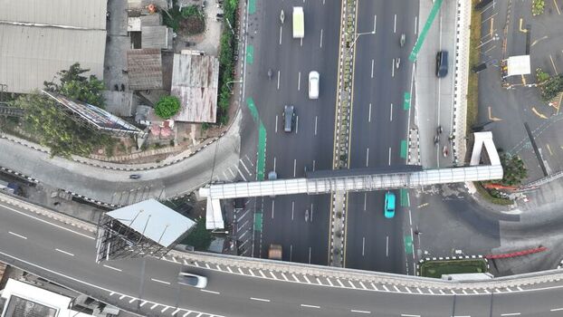 Aerial view of a highway with a pedestrian bridge crossing over traffic in Bekasi Barat West Java Indonesia. Aerial view of a highway with a pedestrian bridge crossing over traffic in Bekasi Barat West Java Indonesia.