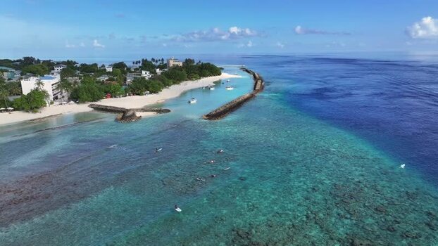 Aerial view of surfers in the turquoise lagoon of Thulusdhoo Maldives.