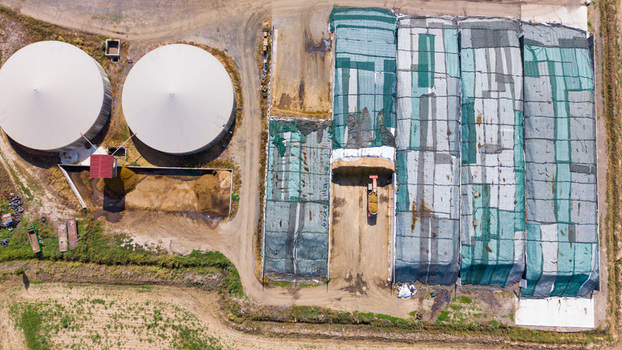 Aerial view of silage pits covered with green tarps and large slurry tanks at a dairy farm in San Giuliano Milanese Lombardy Italy.