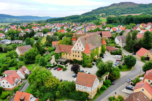 Wiesenthau Germany 09 May 2026 Aerial view of Schloss Wiesenthau with its ivy covered stone walls and red tiled roofs surrounded by the village and green hills of Franconia. Wiesenthau Germany 09 May 2026 Aerial view of Schloss Wiesenthau with its ivy covered stone walls and red tiled roofs surrounded by the village and green hills of Franconia.