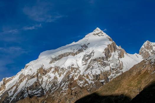 View of K2 peak rising above rocky slopes under a clear blue sky in the Karakoram range Gilgit Baltistan Pakistan. View of K2 peak rising above rocky slopes under a clear blue sky in the Karakoram range Gilgit Baltistan Pakistan.