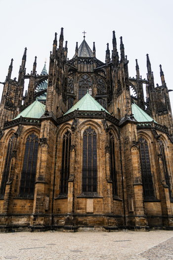 View of the intricate Gothic architecture of St. Vitus Cathedral with its stone walls green copper roofs and tall stained glass windows in Prague Prague Czechia.
