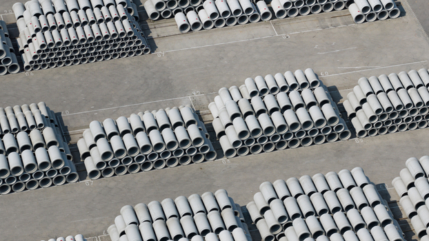 Aerial view of neatly stacked concrete pipes in an industrial storage yard with rows of cylindrical tubes on a paved surface Oosterhout North Brabant Netherlands. Aerial view of neatly stacked concrete pipes in an industrial storage yard with rows of cylindrical tubes on a paved surface Oosterhout North Brabant Netherlands.