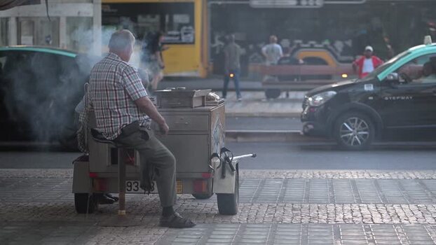 View of a man roasting chestnuts on a street cart in Lisboa Portugal. View of a man roasting chestnuts on a street cart in Lisboa Portugal.