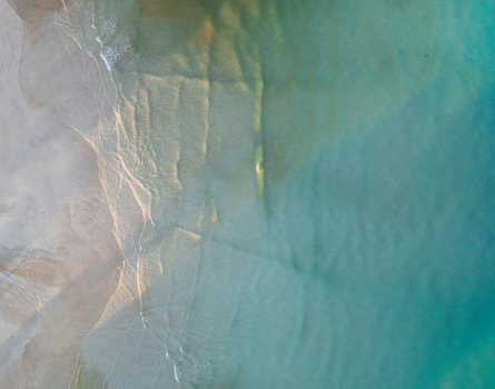 Aerial view of the tranquil sea meeting the shore creating a mesmerizing blend of turquoise and golden hues Pantai Tanjung Aan West Nusa Tenggara Indonesia. Aerial view of the tranquil sea meeting the shore creating a mesmerizing blend of turquoise and golden hues Pantai Tanjung Aan West Nusa Tenggara Indonesia.