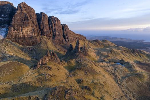Aerial view of the iconic Old Man of Storr rock formations and rugged grassy slopes under soft light on the Isle of Skye Scotland United Kingdom. Aerial view of the iconic Old Man of Storr rock formations and rugged grassy slopes under soft light on the Isle of Skye Scotland United Kingdom.