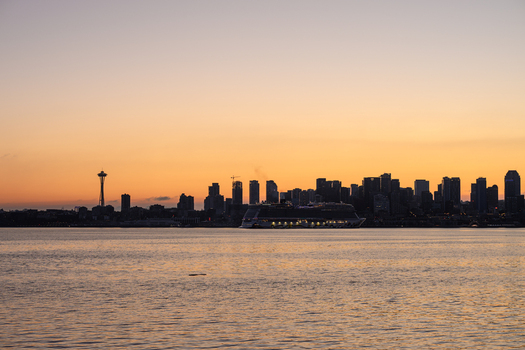 View of the Seattle skyline at sunset with the Space Needle and a large cruise ship on the water captured from the waterfront in Seattle Washington United States. View of the Seattle skyline at sunset with the Space Needle and a large cruise ship on the water captured from the waterfront in Seattle Washington United States.