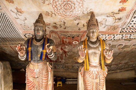 View of ancient standing statues and intricate ceiling murals inside the Dambulla Cave Temple Dambulla Central Province Sri Lanka.