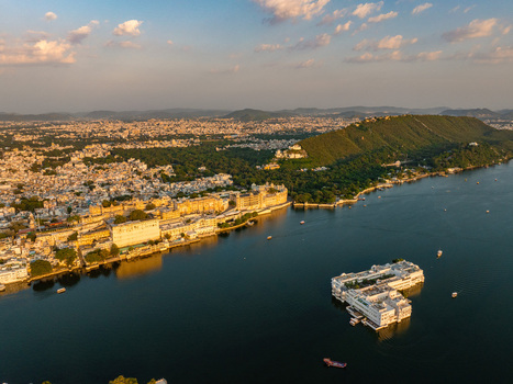 Aerial view of the historic City Palace and Lake Palace situated on the shores of Lake Pichola surrounded by the Aravalli hills in Udaipur Rajasthan India.