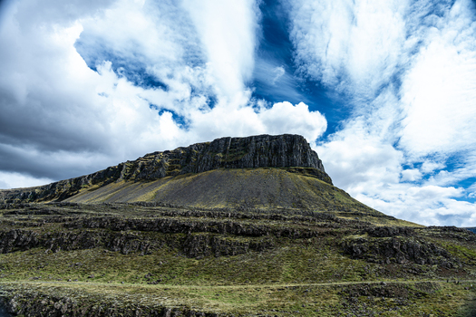 View of the majestic Hvalfjordur mountain with its steep rocky cliffs and mossy slopes under a dramatic cloudy sky Iceland. View of the majestic Hvalfjordur mountain with its steep rocky cliffs and mossy slopes under a dramatic cloudy sky Iceland.