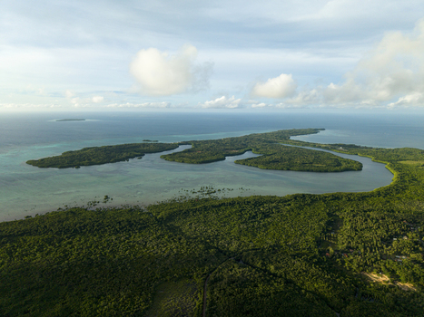 Aerial view of a lush green island surrounded by turquoise waters and distant clouds Karimunjawa Central Java Indonesia.