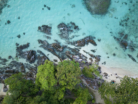 Aerial view of turquoise waters meet rugged rocks and verdant trees at Tanjung Gelam Beach a tropical oasis Karimunjawa Central Java Indonesia. Aerial view of turquoise waters meet rugged rocks and verdant trees at Tanjung Gelam Beach a tropical oasis Karimunjawa Central Java Indonesia.