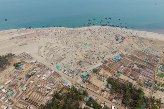Cox s Bazar Bangladesh 11 March 2026 Aerial view of fishing nets spread across the sandy beach with numerous wooden boats anchored in the turquoise sea and a coastal village nearby. Cox s Bazar Bangladesh 11 March 2026 Aerial view of fishing nets spread across the sandy beach with numerous wooden boats anchored in the turquoise sea and a coastal village nearby.