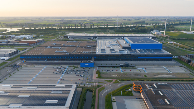 Waalwijk Netherlands 09 May 2026 Aerial view of the massive Bol.com distribution center with its blue facade surrounding parking lots and wind turbines under a sunset sky. Waalwijk Netherlands 09 May 2026 Aerial view of the massive Bol.com distribution center with its blue facade surrounding parking lots and wind turbines under a sunset sky.