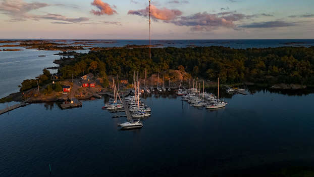 Aerial view of Oro Fortress Island marina with sailboats and motorboats docked at wooden piers surrounded by forest and red buildings under a sunset sky Oro Varsinais Suomi Finland. Aerial view of Oro Fortress Island marina with sailboats and motorboats docked at wooden piers surrounded by forest and red buildings under a sunset sky Oro Varsinais Suomi Finland.