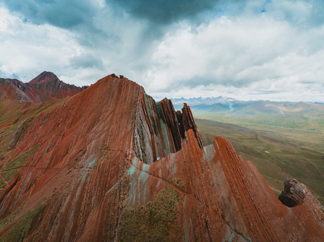 Aerial view of the dramatic striated rock formations of Pallay Punchu Rainbow Mountain under a cloudy sky in Layo Cuzco Peru.