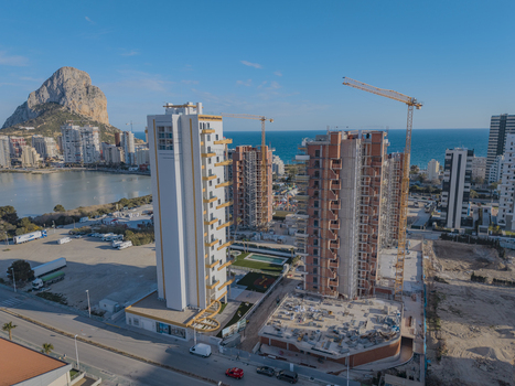 Aerial view of high rise buildings under construction with tall cranes overlooking the Mediterranean Sea and the Penon de Ifach rock formation in Calp Valencian Community Spain. Aerial view of high rise buildings under construction with tall cranes overlooking the Mediterranean Sea and the Penon de Ifach rock formation in Calp Valencian Community Spain.