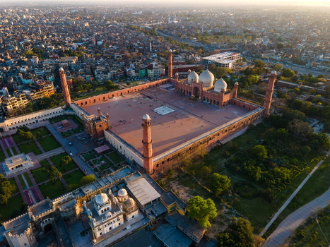 Aerial view of Badshahi Mosque with its iconic red sandstone walls white marble domes and expansive courtyard set against the dense urban landscape of Lahore Punjab Pakistan. Aerial view of Badshahi Mosque with its iconic red sandstone walls white marble domes and expansive courtyard set against the dense urban landscape of Lahore Punjab Pakistan.