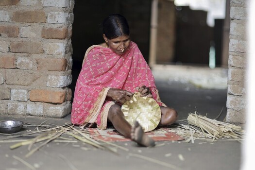 Odisha India 26 March 2026 View of a woman with her hands deftly weaving a vibrant circular mat against the rustic backdrop of a brick doorway. Odisha India 26 March 2026 View of a woman with her hands deftly weaving a vibrant circular mat against the rustic backdrop of a brick doorway.