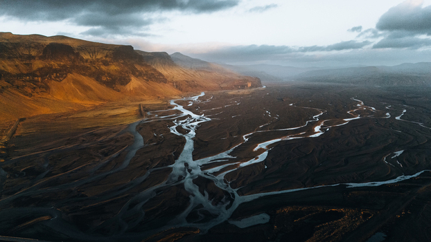 Aerial view of Lomagnupur mountain and the intricate braided glacial river channels flowing through dark volcanic plains in Skaftarhreppur Iceland.