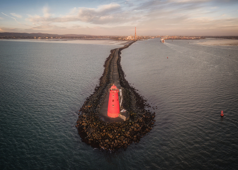 Aerial view of the red Poolbeg Lighthouse at the end of the Great South Wall pier in Dublin Bay during sunset Dublin County Dublin Ireland.