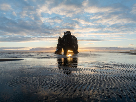 Aerial view of the Hvitserkur rock formation standing on a sandy beach with intricate tidal patterns and golden hour light reflecting on the wet sand in Iceland. Aerial view of the Hvitserkur rock formation standing on a sandy beach with intricate tidal patterns and golden hour light reflecting on the wet sand in Iceland.