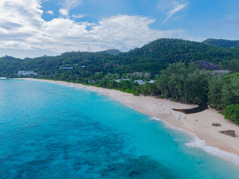 Aerial view of turquoise waters meet the sandy shore fringed by lush green trees and distant hills Quatre Bornes Mahe Island Seychelles. Aerial view of turquoise waters meet the sandy shore fringed by lush green trees and distant hills Quatre Bornes Mahe Island Seychelles.
