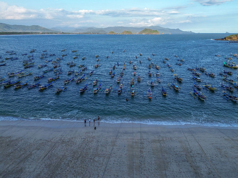 Aerial view of Papuma Beach with numerous traditional fishing boats anchored in the blue water along the sandy coastline in Jember East Java Indonesia. Aerial view of Papuma Beach with numerous traditional fishing boats anchored in the blue water along the sandy coastline in Jember East Java Indonesia.