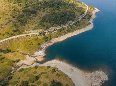 Aerial view of Belmeken Reservoir with a winding road along the shoreline grassy slopes and coniferous trees Pazardzhik Bulgaria. Aerial view of Belmeken Reservoir with a winding road along the shoreline grassy slopes and coniferous trees Pazardzhik Bulgaria.