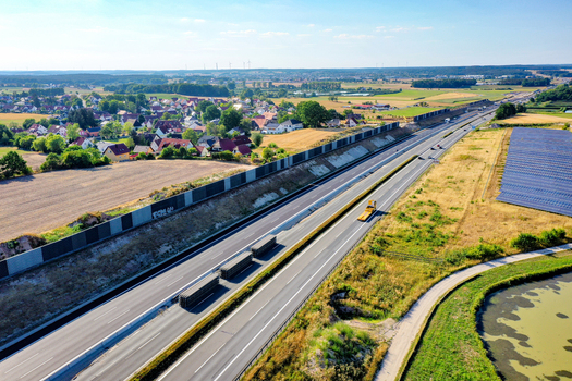 Nurnberg Germany 18 May 2024 Aerial view of the A73 highway with noise protection walls trucks and solar panels near a village in Bayern. Nurnberg Germany 18 May 2024 Aerial view of the A73 highway with noise protection walls trucks and solar panels near a village in Bayern.