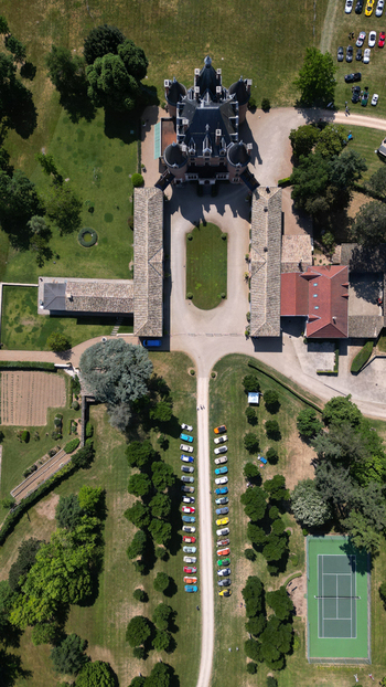 Francheleins France 04 June 2023 Aerial view of Chateau de Vataneins with colorful cars parked along the driveway a tennis court and lush green gardens in the French countryside. Francheleins France 04 June 2023 Aerial view of Chateau de Vataneins with colorful cars parked along the driveway a tennis court and lush green gardens in the French countryside.