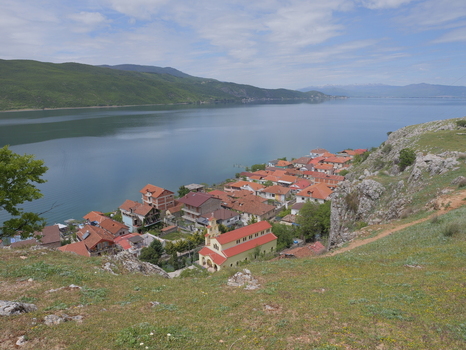 View of the village of Lin with its red roofed houses and a prominent church situated on the shore of Lake Ohrid surrounded by green hills and clear blue water in Lin Korce County Albania.
