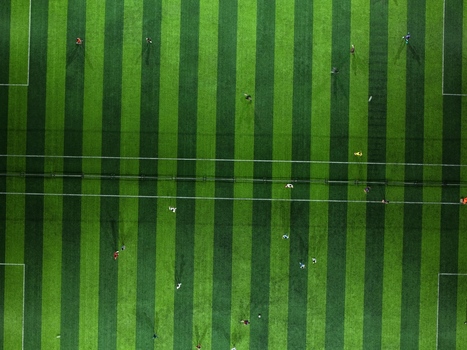 Aerial view of Bravo Arena soccer field with players in motion on the green pitch in Kecamatan Denpasar Selatan Bali Indonesia.