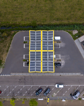 Aerial view of the Fastned charging station with solar panel roof parked electric vehicles and surrounding asphalt infrastructure in Beesd Gelderland Netherlands. Aerial view of the Fastned charging station with solar panel roof parked electric vehicles and surrounding asphalt infrastructure in Beesd Gelderland Netherlands.