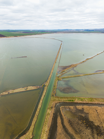 Aerial view of Lake Atanasovsko featuring salt pans and a long canal surrounded by grassy banks under a cloudy sky in Burgas Burgas Bulgaria. Aerial view of Lake Atanasovsko featuring salt pans and a long canal surrounded by grassy banks under a cloudy sky in Burgas Burgas Bulgaria.