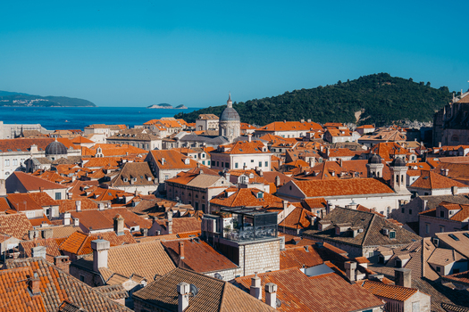 View of the historic red terracotta rooftops and stone buildings of the Old Town with the Adriatic Sea and green hills in Dubrovnik Dubrovnik Neretva County Croatia. View of the historic red terracotta rooftops and stone buildings of the Old Town with the Adriatic Sea and green hills in Dubrovnik Dubrovnik Neretva County Croatia.