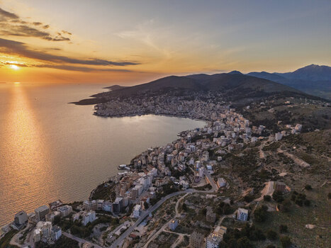 Aerial view of the coastal city of Saranda at sunset featuring the urban landscape along the Ionian Sea rolling hills and golden light in Saranda Vlore County Albania. Aerial view of the coastal city of Saranda at sunset featuring the urban landscape along the Ionian Sea rolling hills and golden light in Saranda Vlore County Albania.