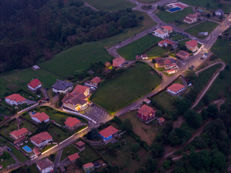 Aerial view of illuminated houses with red roofs nestled on a green hillside during twilight in the coastal village of Cudillero Asturias Spain. Aerial view of illuminated houses with red roofs nestled on a green hillside during twilight in the coastal village of Cudillero Asturias Spain.