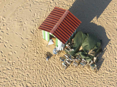 Aerial view of a small striped beach hut with a red roof and stacked chairs on the sand at Praia da Figueira da Foz Coimbra District Portugal.