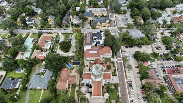 Aerial view of the historic Cathedral Basilica of St. Augustine surrounded by lush trees red tile rooftops and urban streets in St. Augustine Florida United States. Aerial view of the historic Cathedral Basilica of St. Augustine surrounded by lush trees red tile rooftops and urban streets in St. Augustine Florida United States.