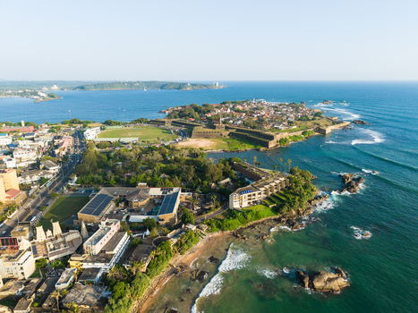 Aerial view of Galle Fort with its historic stone walls terracotta rooftops and the turquoise Indian Ocean coastline under a clear blue sky Galle Southern Province Sri Lanka.