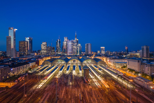 Aerial view of Hauptbahnhof with illuminated train platforms and the city skyline under a twilight sky in Frankfurt am Main Hessen Germany.