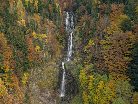 Aerial view of the Pyrenees waterfall cascading down rocky cliffs surrounded by vibrant autumn foliage in Spain. Aerial view of the Pyrenees waterfall cascading down rocky cliffs surrounded by vibrant autumn foliage in Spain.