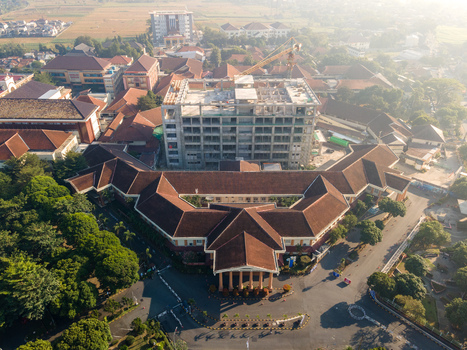 Aerial view of an institutional building complex with red tiled roofs and a central courtyard featuring a concrete structure under construction in Banyumas Regency Central Java Indonesia.